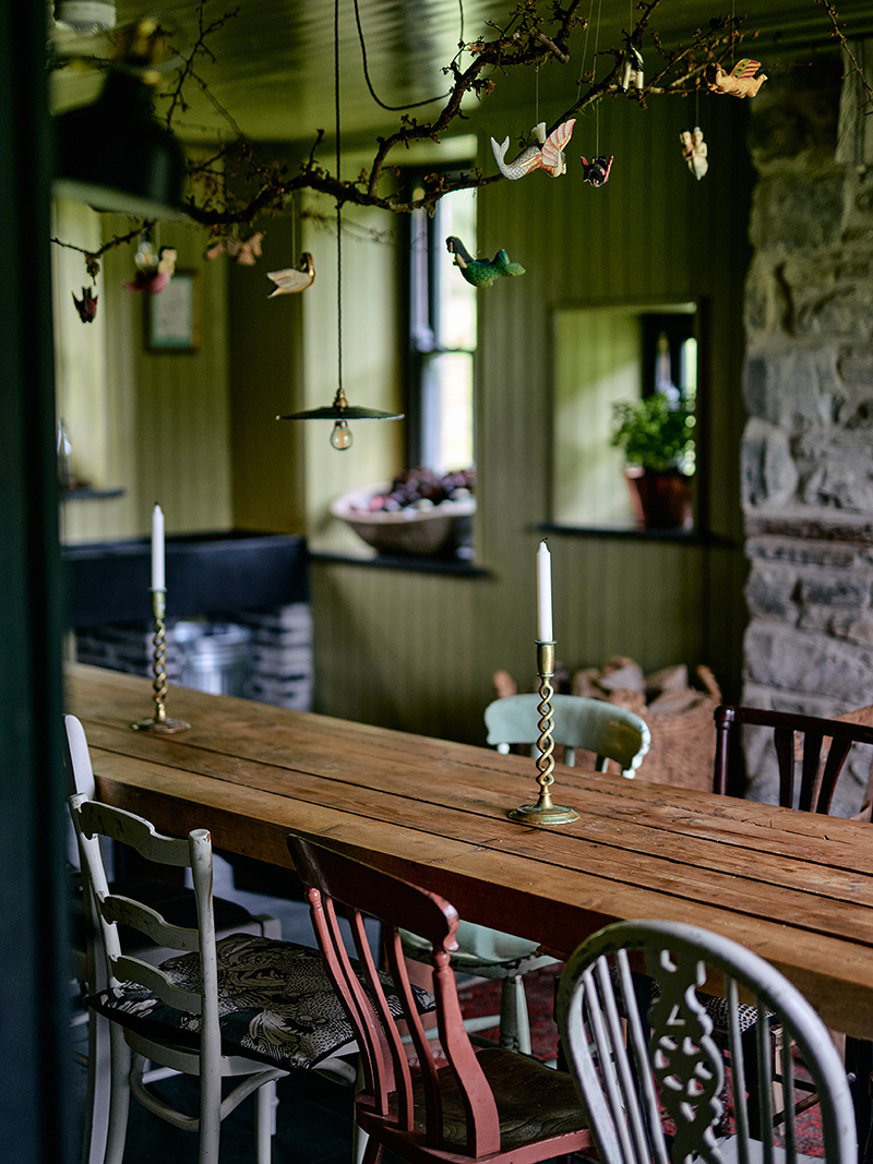 Table de ferme avec une série de chaises dépareillées en bois peintes dans des couleurs différentes