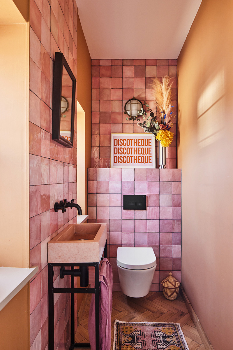 Des toilettes en zelliges rose, associées à des murs orange saumoné