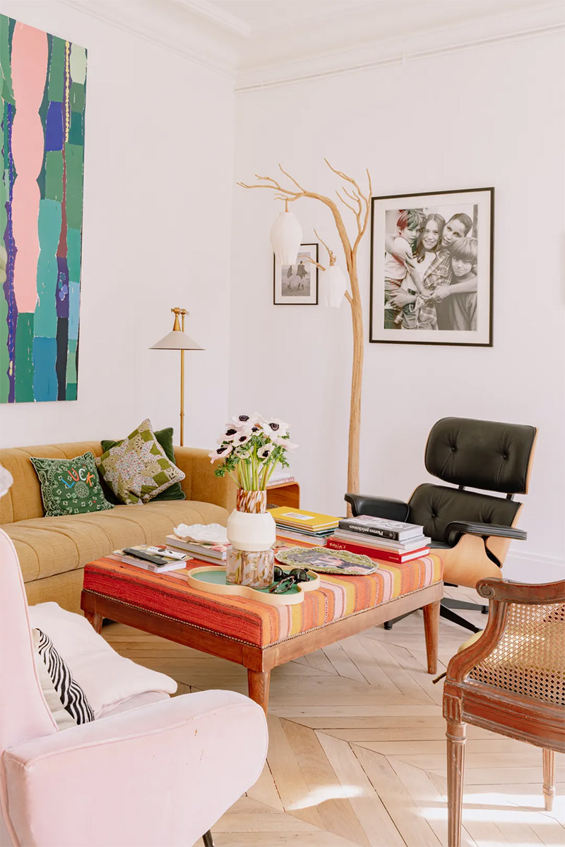 Un salon haussmannien blanc, décoré avec des meubles et des œuvres colorés Un salon haussmannien blanc, décoré avec des meubles et des œuvres colorés pour une énergie de vacances