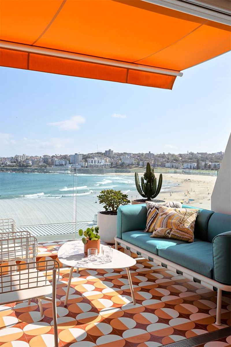 Une terrasse en mode seventies par Greg Natale avec un store banne orange