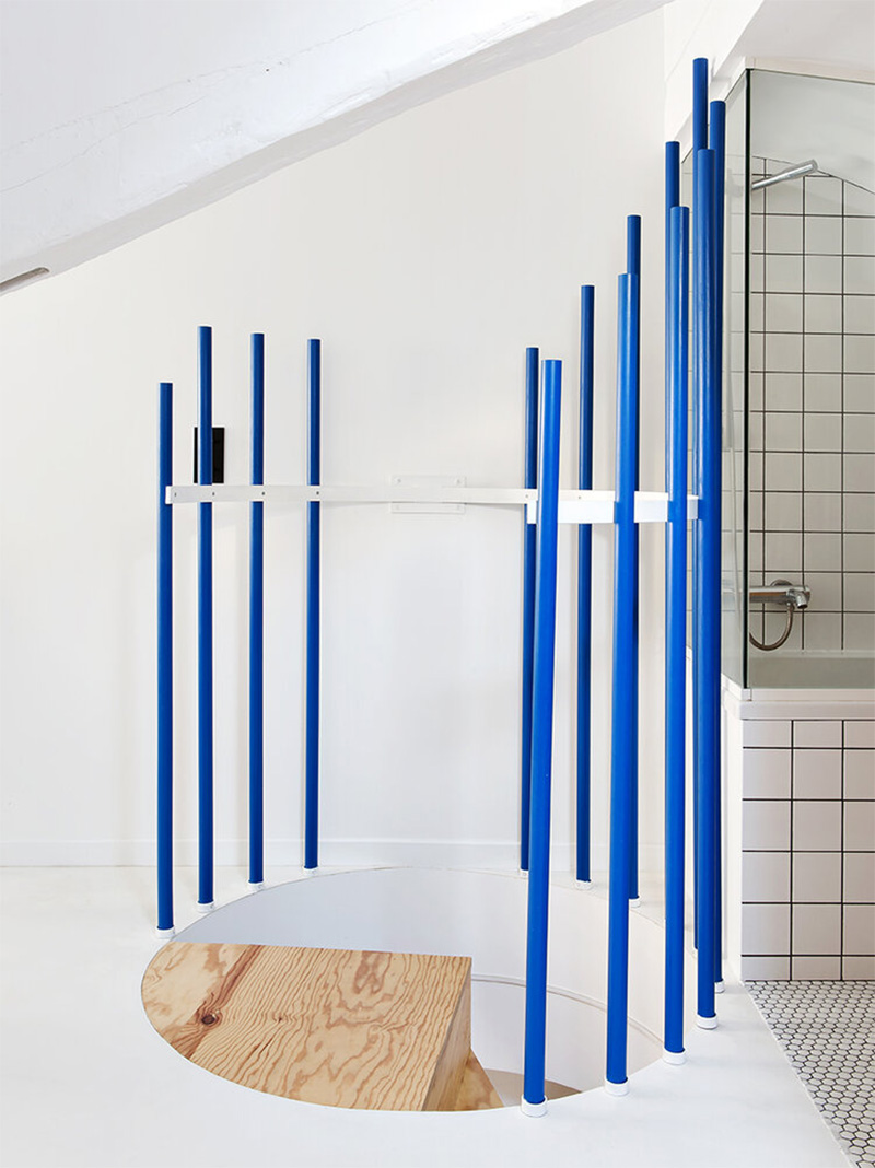 Les montants d'un escalier peints en bleu électrique dans un décor complètement blanc