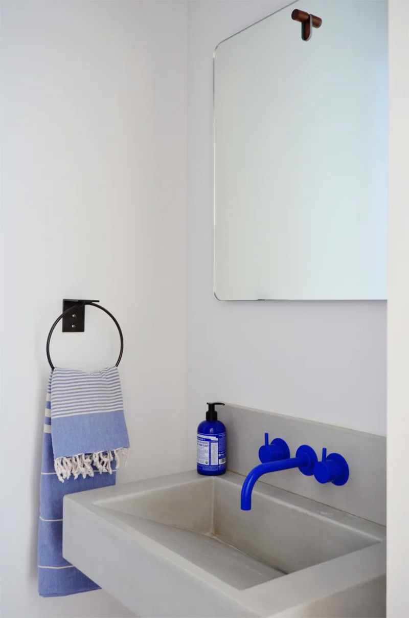 Des robinets en bleu électrique associé à un lavabo en béton ciré