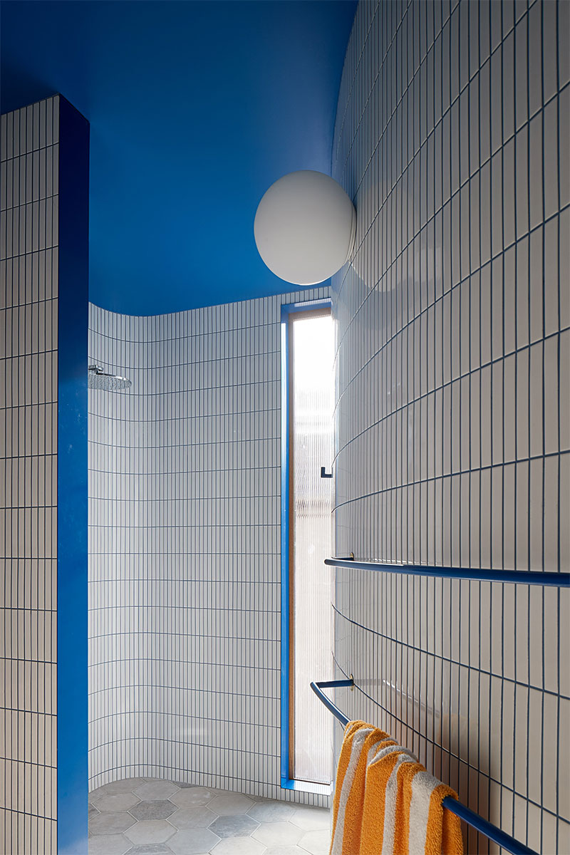 Une salle de douche tout en courbe en carrelage blanc et murs bleus