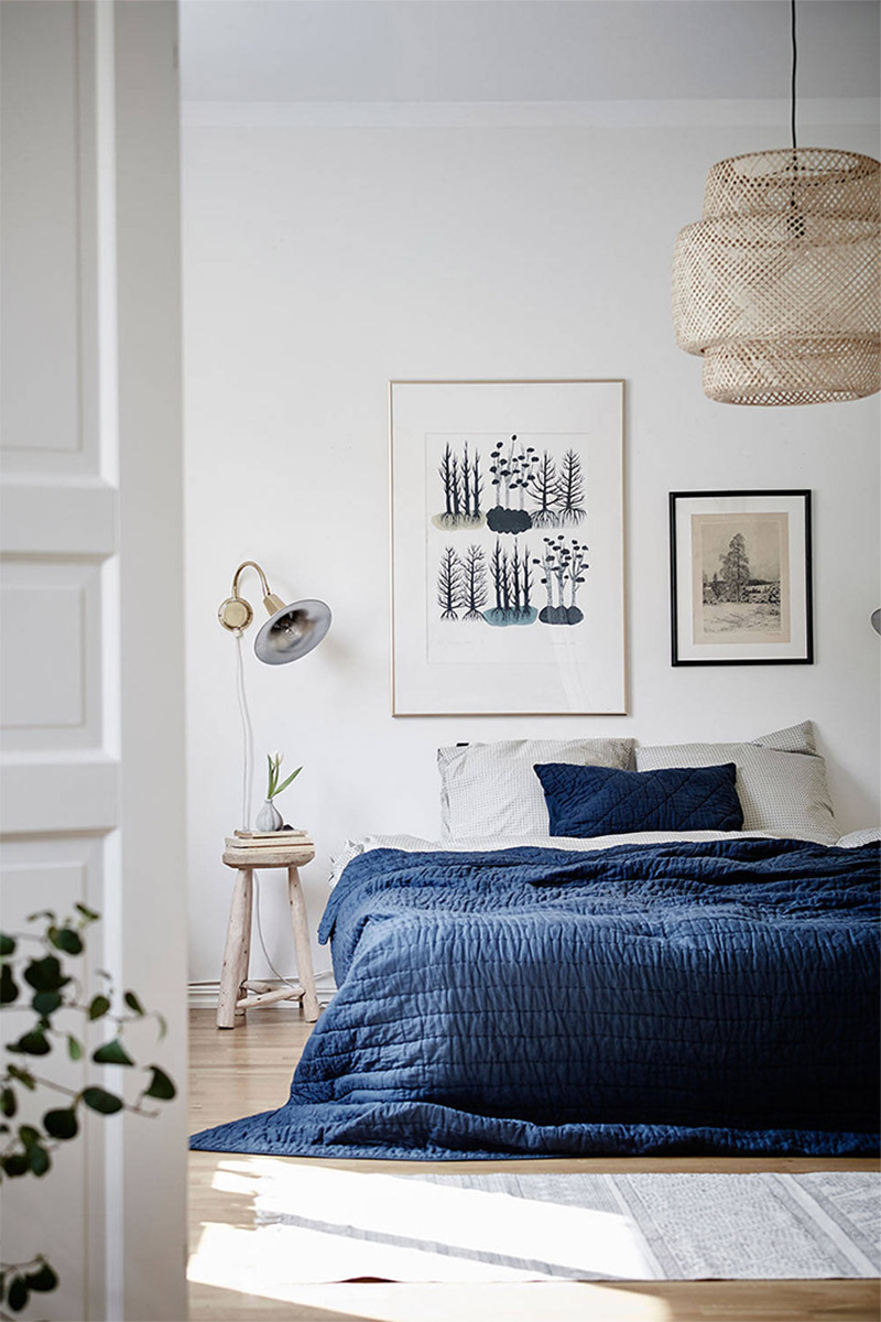 Une chambre de style scandicraft blanche ravivé par un beau dessus de lit bleu