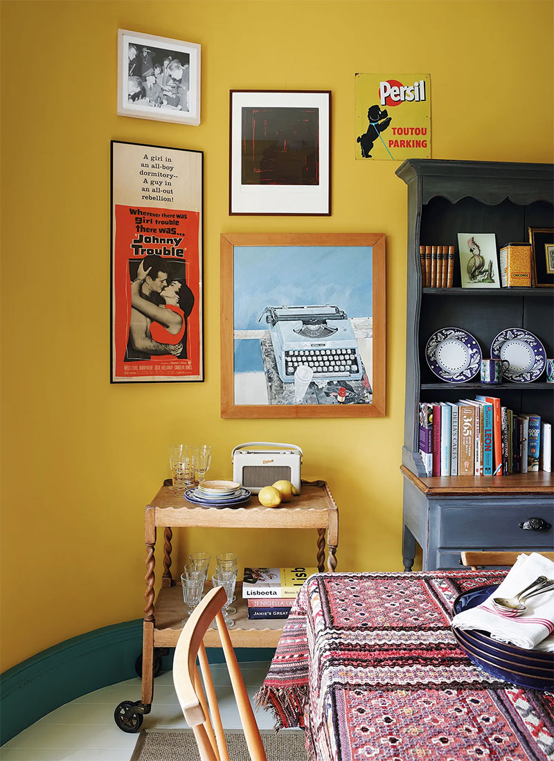 Accrochage de cadre sur mur jaune dans la cuisine de la designer Susan Deliss à Edinbourg