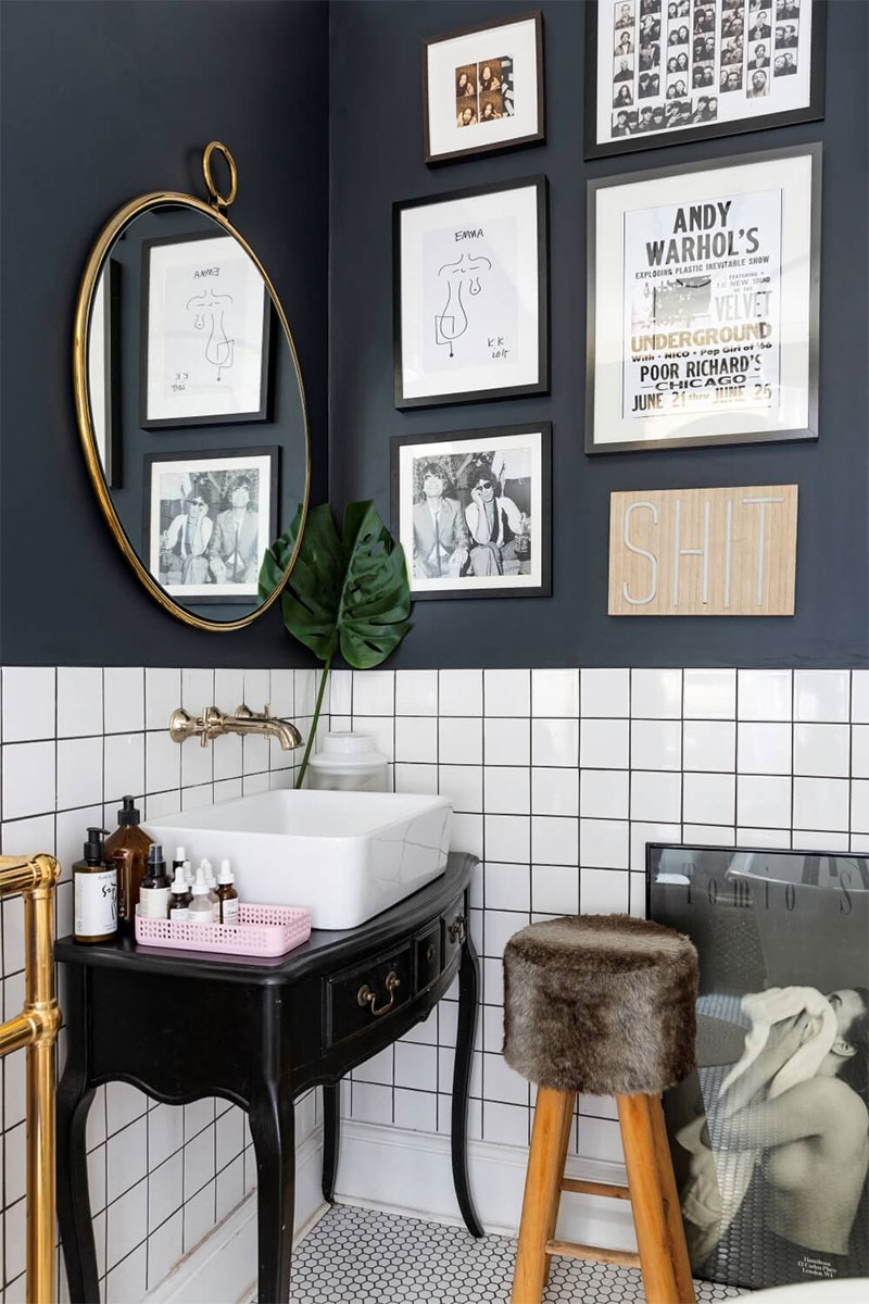 Une salle de bains pimpée avec une série de cadres sur un mur noir
