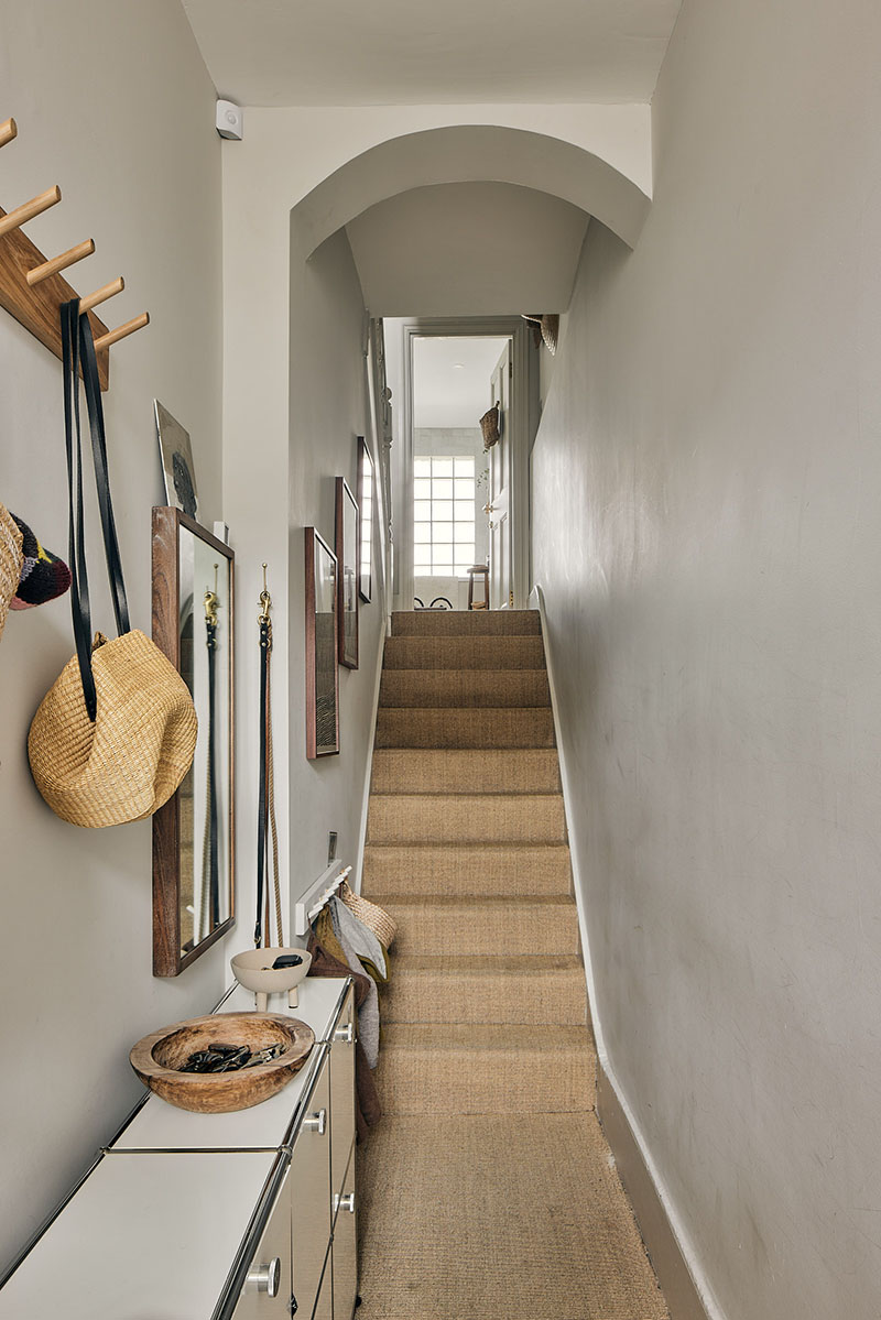 Un escalier "old new" protégé par de la fibre coco et des murs peints en blanc cassé