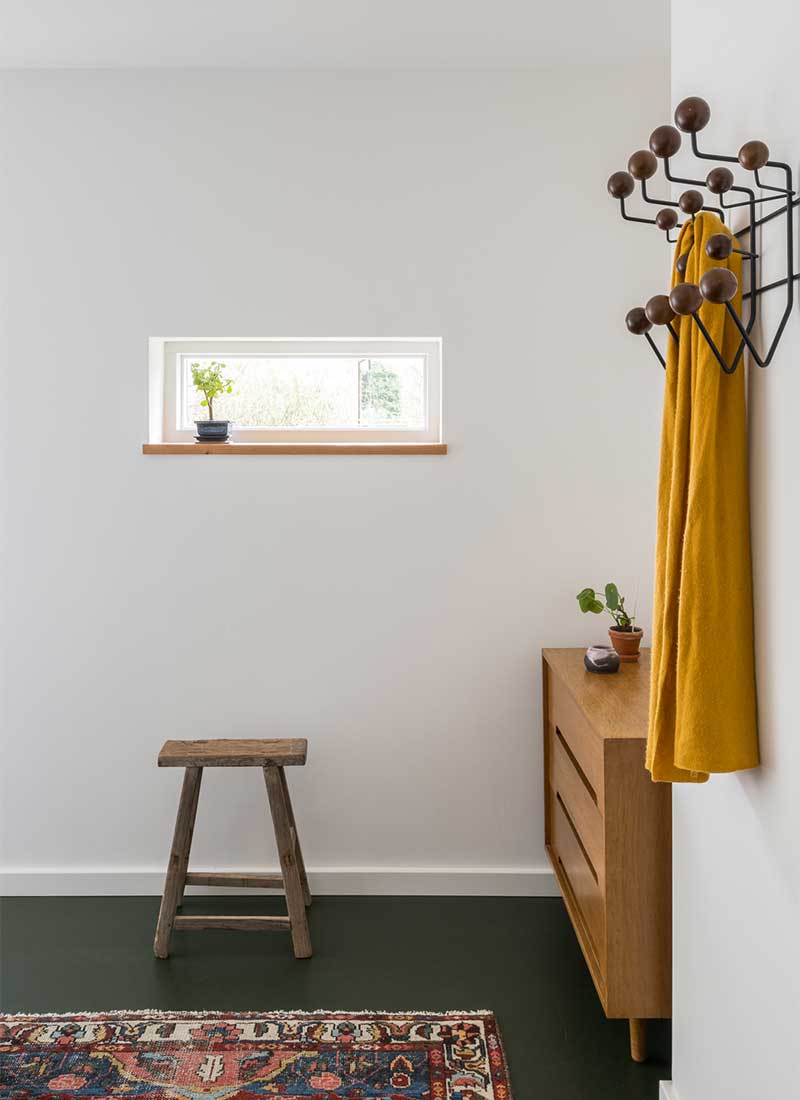 Une chambre moderne blanche avec un sol en linoléum vert sapin, associé à du mobilier vintage