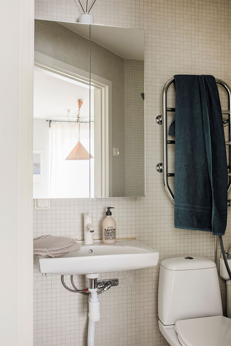 Micro salle d'eau équipée d'un sèche serviette chromé, placé au-dessus des toilettes