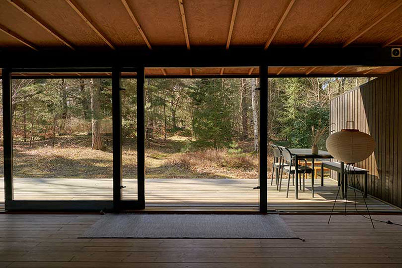 Un cabanon avec de grandes baies vitrées ouvertes sur l'environnement extérieur