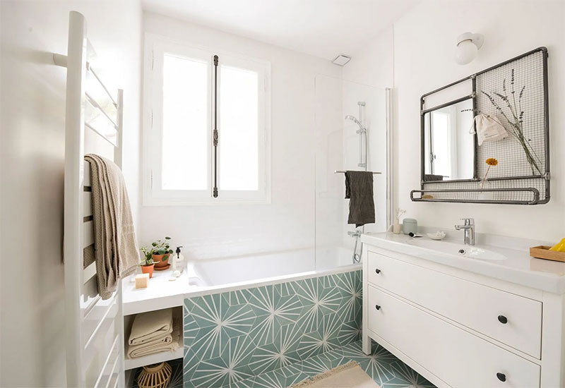 Sèche serviette blanc sur mur blanc. Le look de cette salle de bains blanche est réhaussé par le choix d'un carrelage en carreaux de ciment vert d'eau.