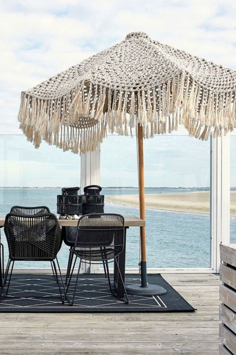 Parasol en macramé sur terrasse en bois, face à la mer