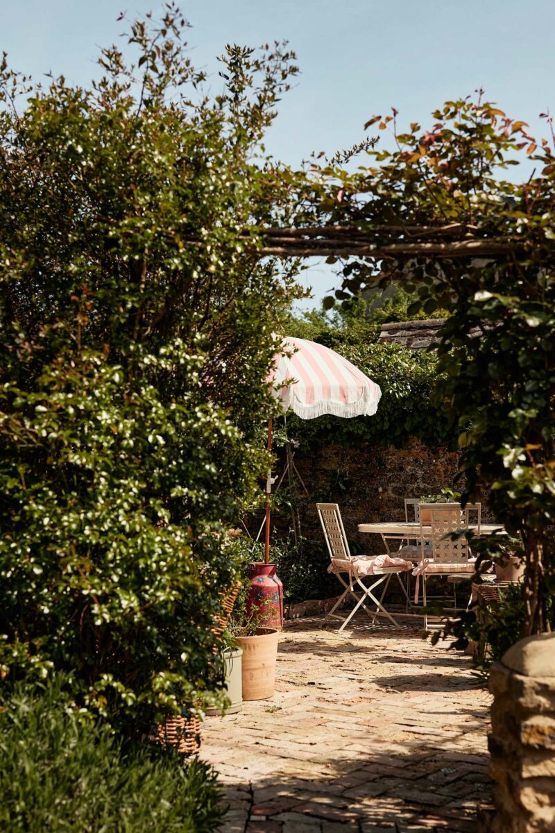 Extérieur avec son parasol rétro à rayures rose et blanc dans un cottage anglais