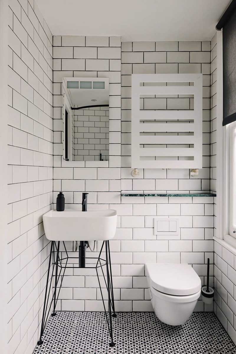 Une salle d'eau en noir et blanc avec carreaux de faïence blancs du sol au plafond