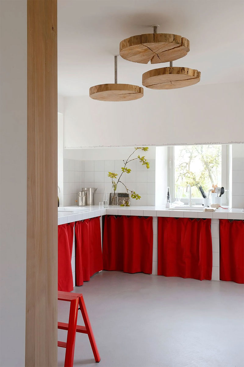 Une cuisine blanche d'inspiration méditerranéenne avec des rideaux de placards rouge vif