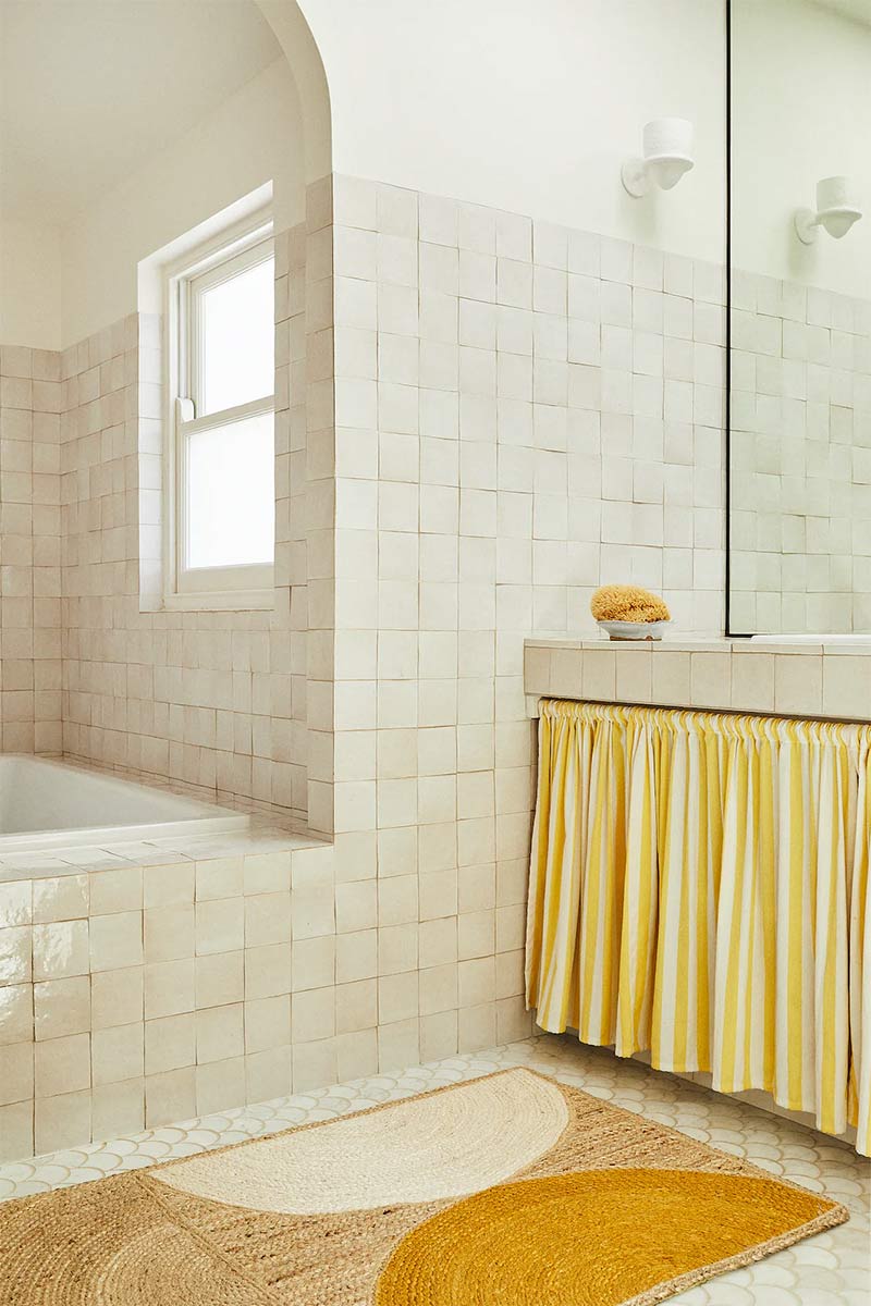 Salle de bains en zelliges crème avec un rideau jupon rayé balnc et jaune