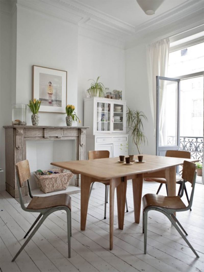 Un style brocante épurée pour cette salle à manger aux chaises d'écolier vintage dans cet appartement bruxellois