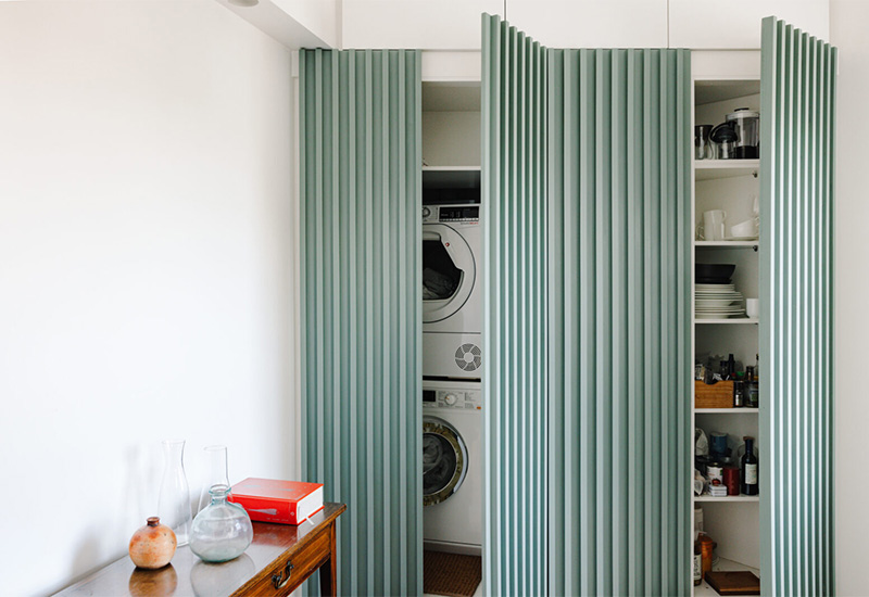 Une cuisine ultramoderne dans un petit appartement dans des tonalités de bleu canard à vert d'eau