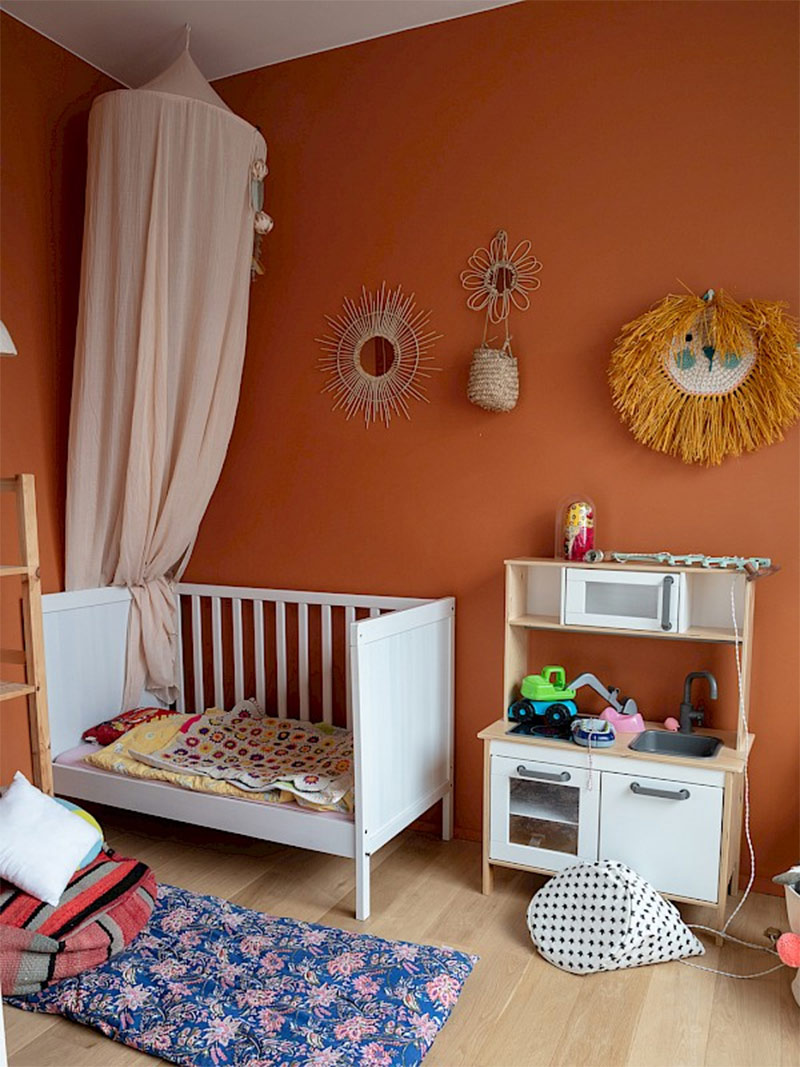 Une chambre d'enfant de style bohème avec un mur terracotta