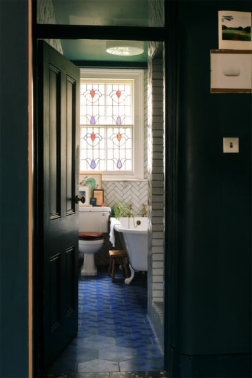 Une salle de bains vintage avec une fenêtre en vitraux