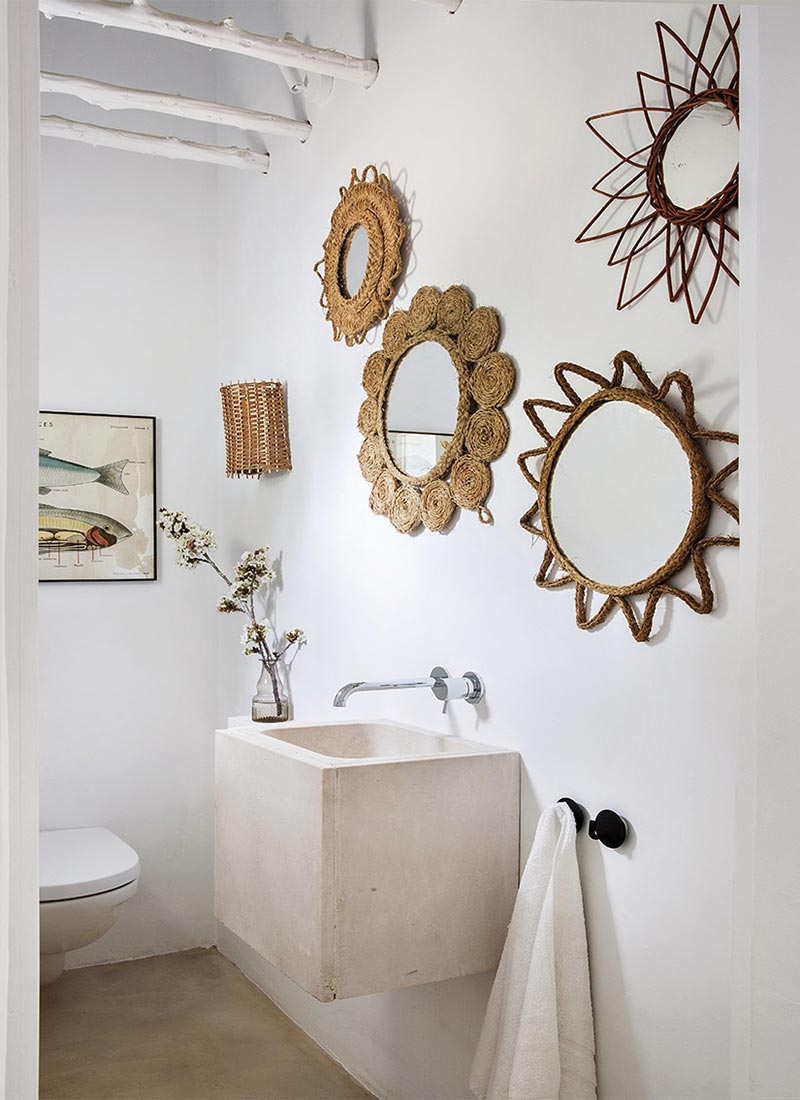 La salle de bains de style méditerranéen ethnique chic et blanche avec sa collection de miroirs soleil en corde