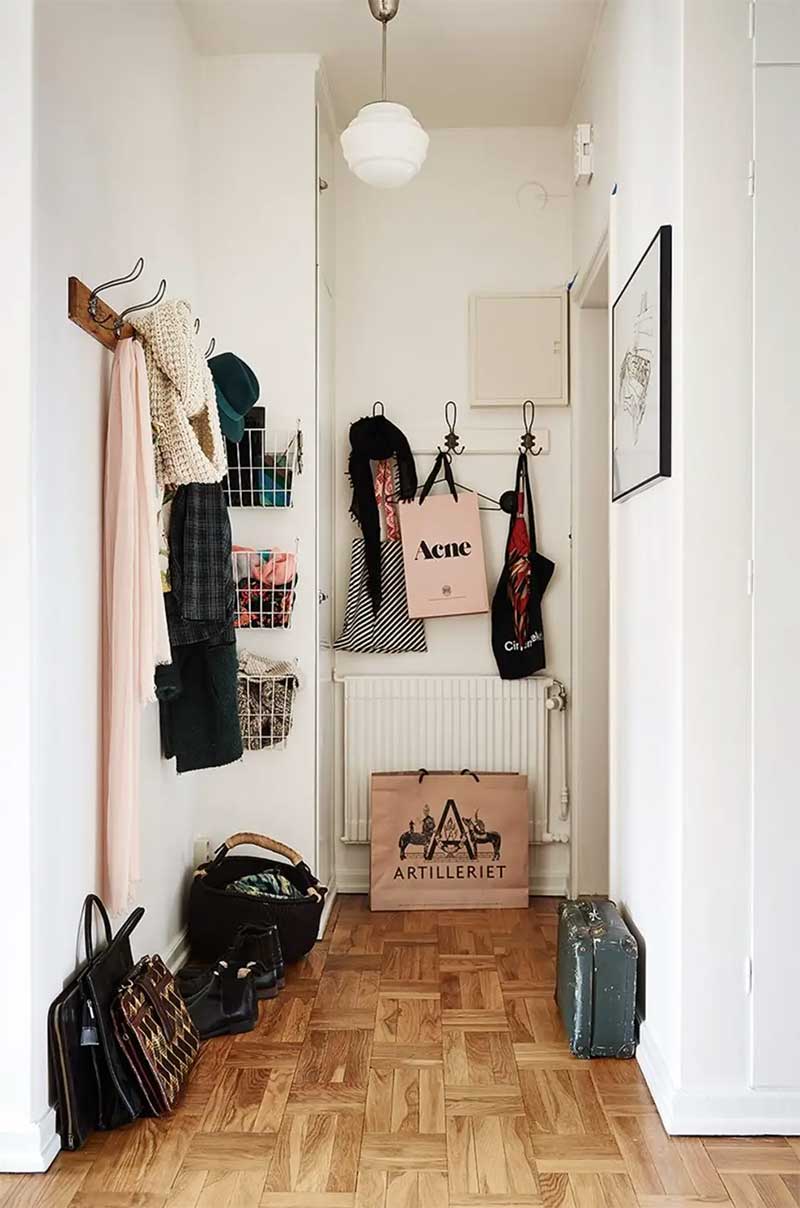 Entrée d'appartement avec de nombreux accessoires de rangement muraux : paniers muraux et porte-manteaux