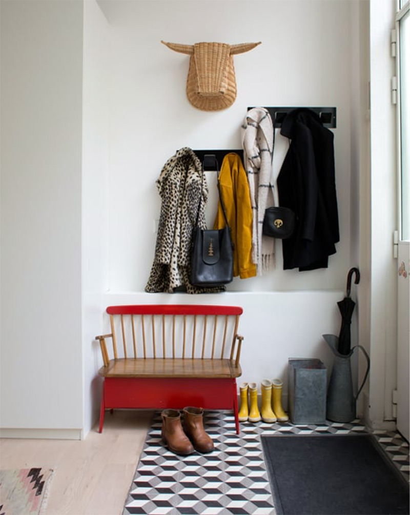 Entrée de maison simple et réussie avec ses porte-manteaux, ses sceaux à parapluie et sa petite touche déco