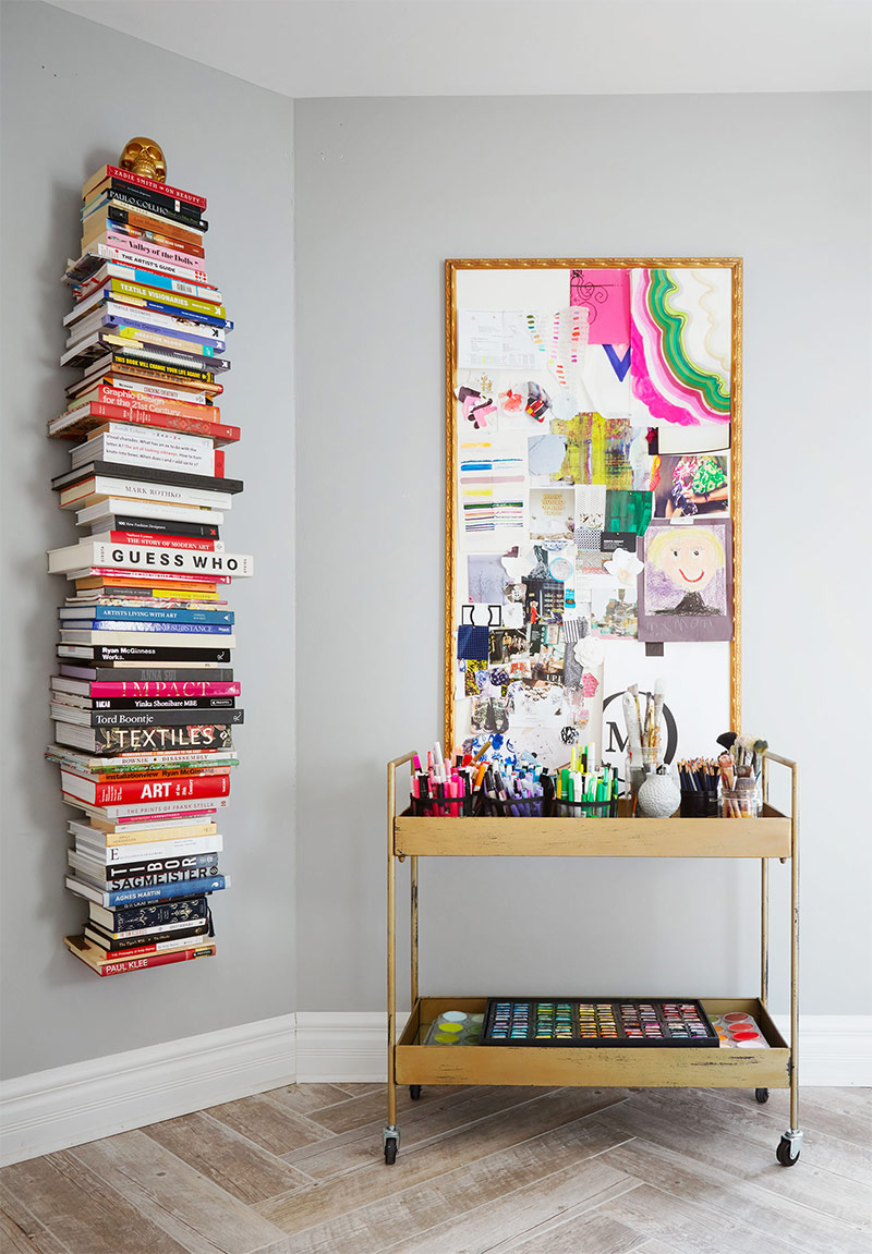 Étagère murale verticale de livres colorés dans un angle du studio de Hapi Art
