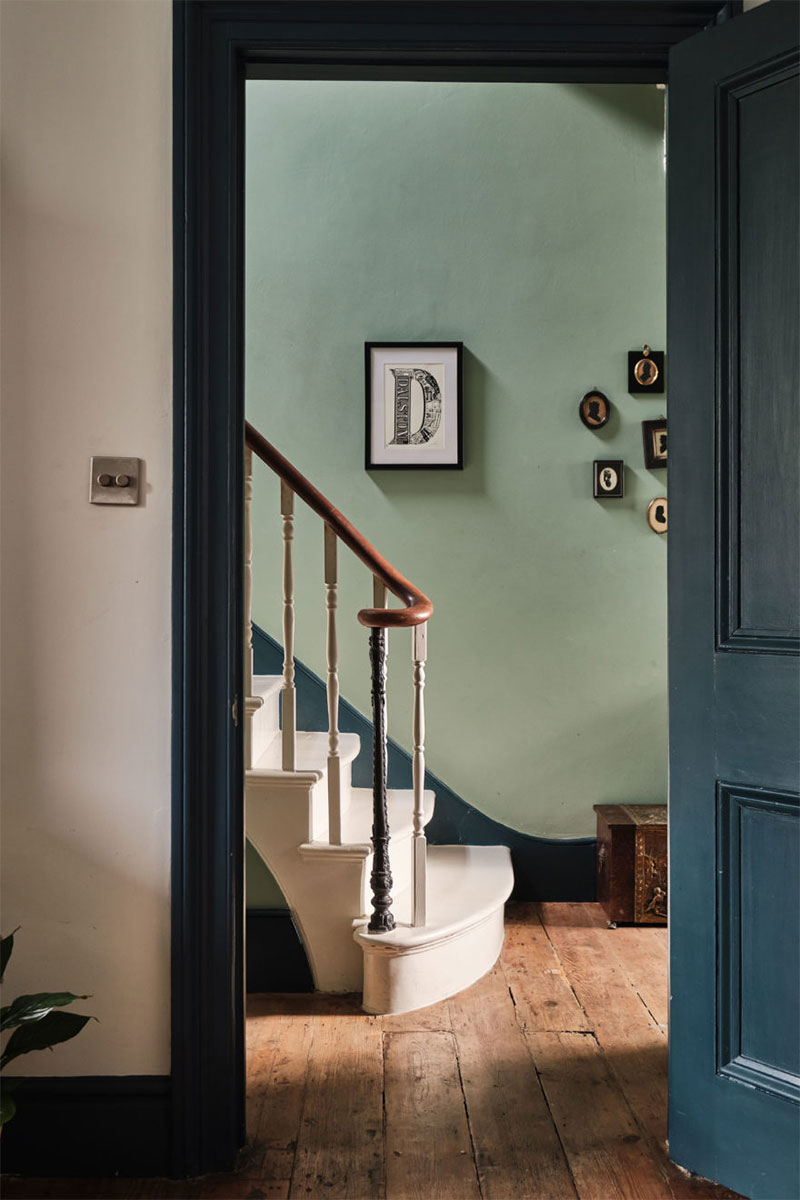 Un cadre de porte en bleu profond pour mettre en valeur le pied de l'escalier