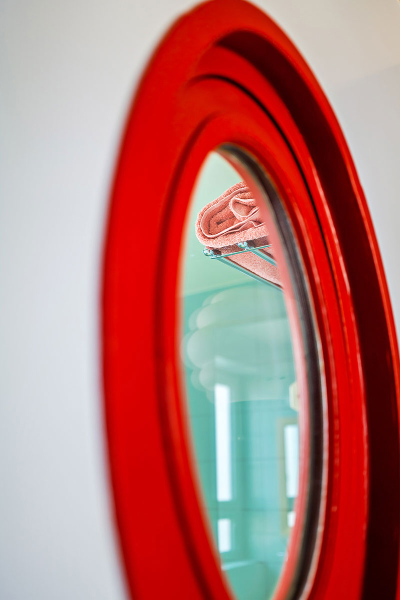 Un miroir rouge vif pour une salle de bain vert d'eau