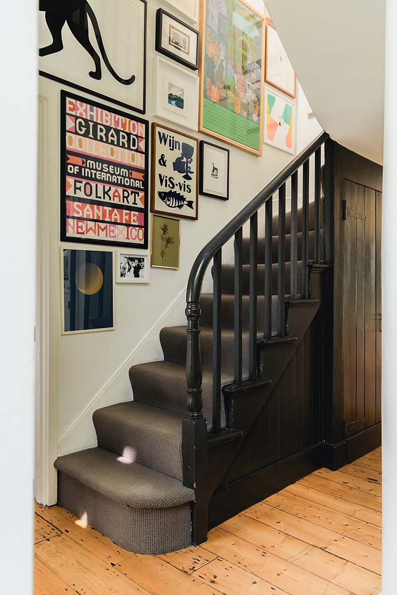 Un escalier noir avec un bel accrochage de cadres éclectiques