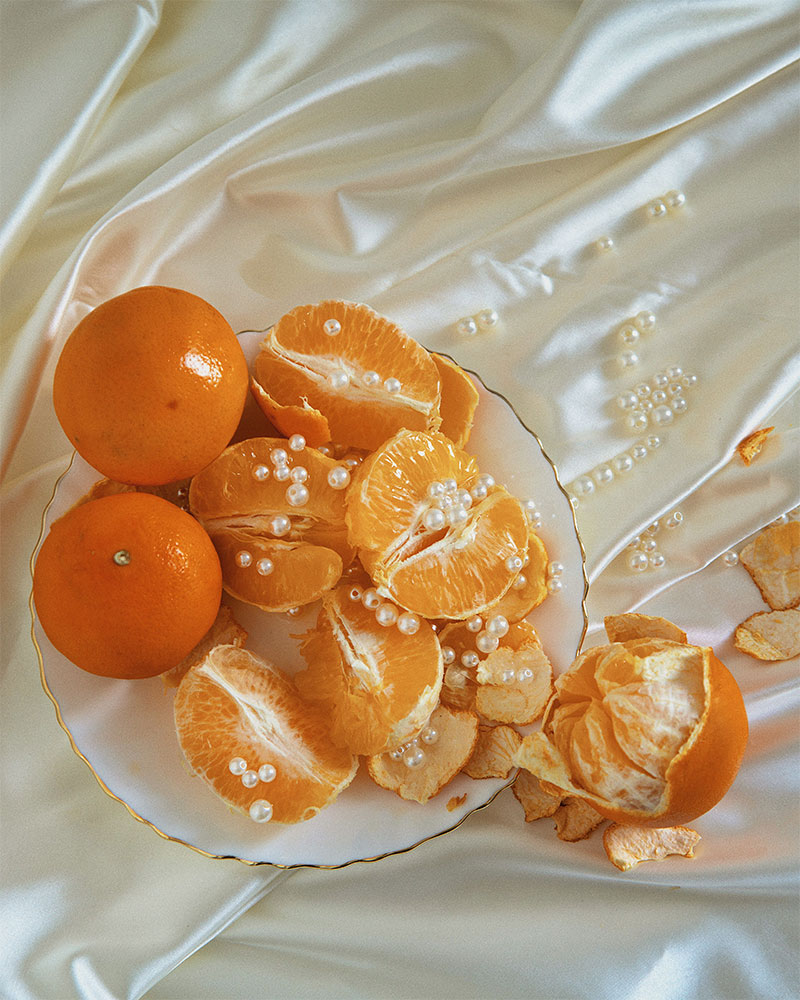 Mandarines ouvertes décorées de perle sur nappe de satin