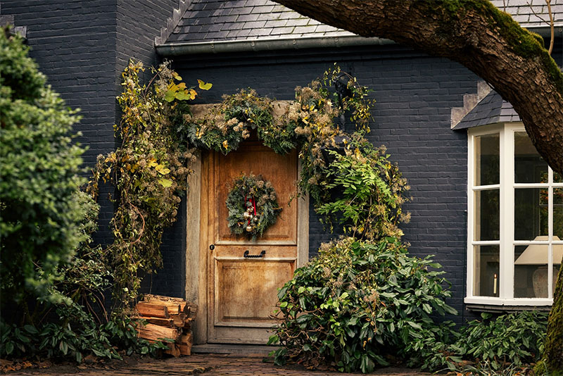 Catalogue de Noël Zara Home 2023 - Porche de maison avec une décoration végétale pour les fêtes de fin d'année