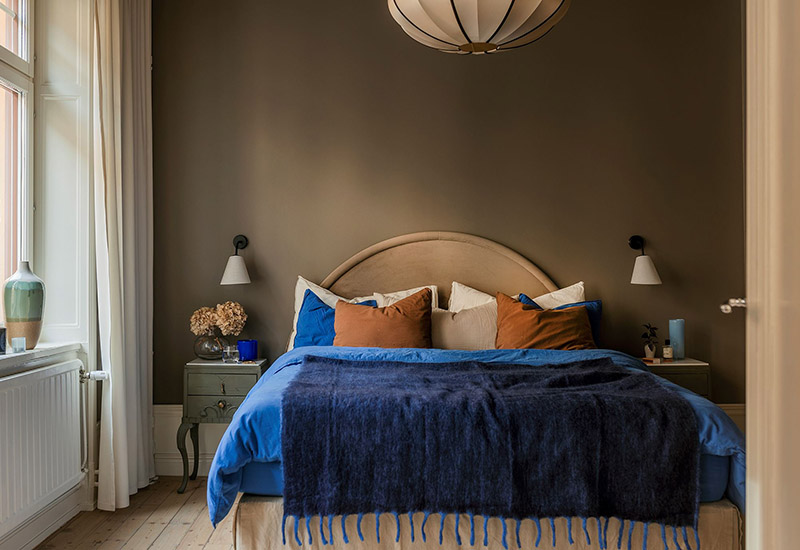 Une chambre lagom avec des murs taupe et linge de lit bleu roi