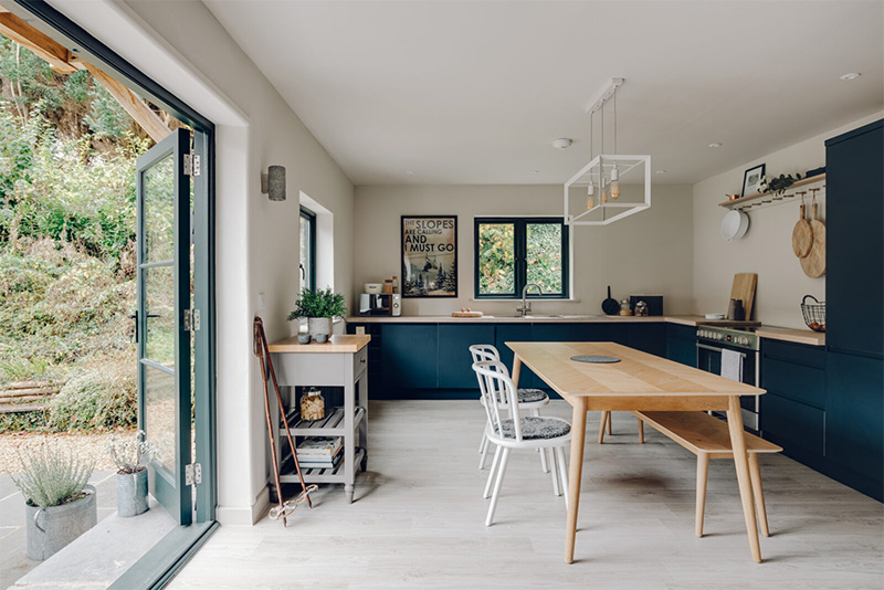 Vue sur la cuisine avec des placards de cuisine bleu et plan de travail en bois