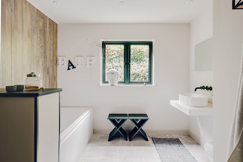 La salle de bains de style nordique blanche avec un parement bois pour la baignoire