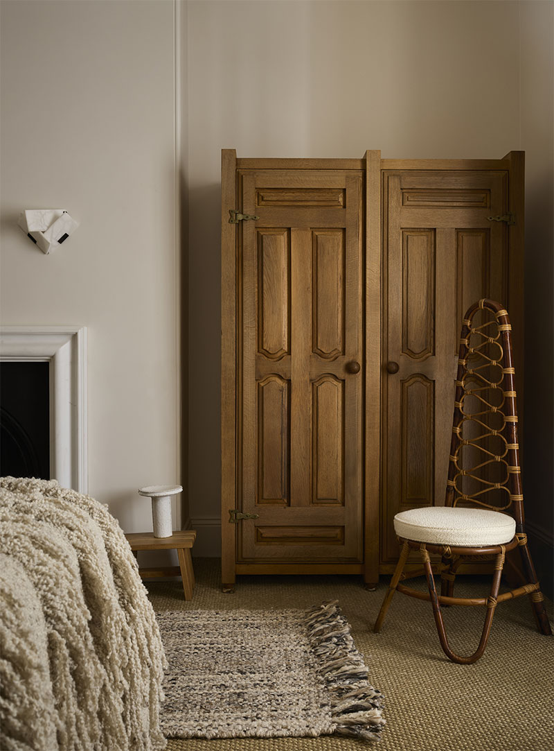 La chambre avec sa vieille armoire et un fauteuil en rotin dans des tonalités de beiges