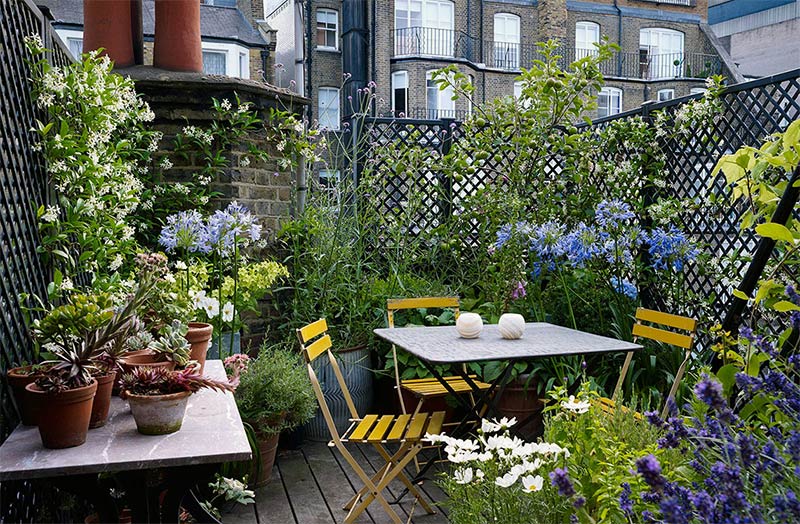 Une terrasse de ville sur les toits aménagée avec un micro jardin fleuri et foisonnant