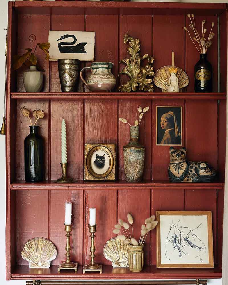 Une étagère fabriquée avec des planches, peinte en rouge pour exposer des menus objets chinés