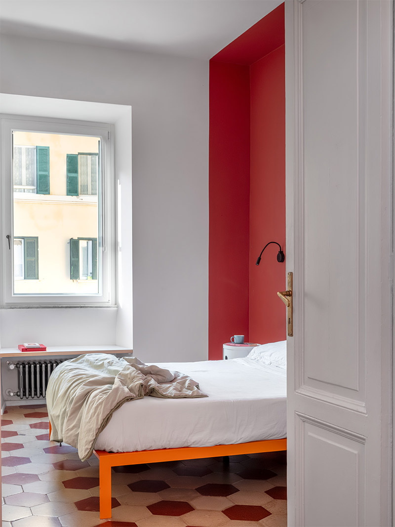 Alcôve créée avec une peinture rouge pour marquer une tête de lit dans une chambre blanche