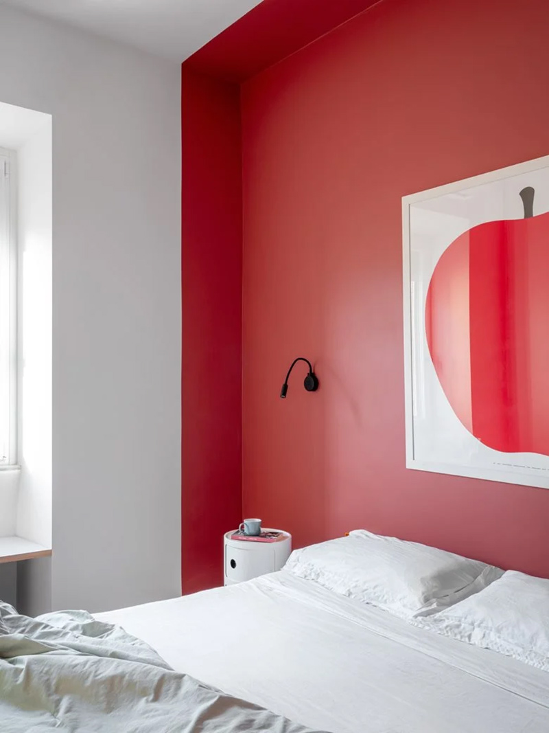 Alcôve créée avec une peinture rouge pour marquer une tête de lit dans une chambre blanche