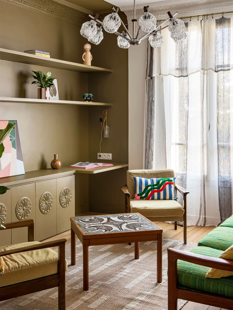 Un mur peint en vert olive pour souligner une bibliothèque ouverte dans un salon