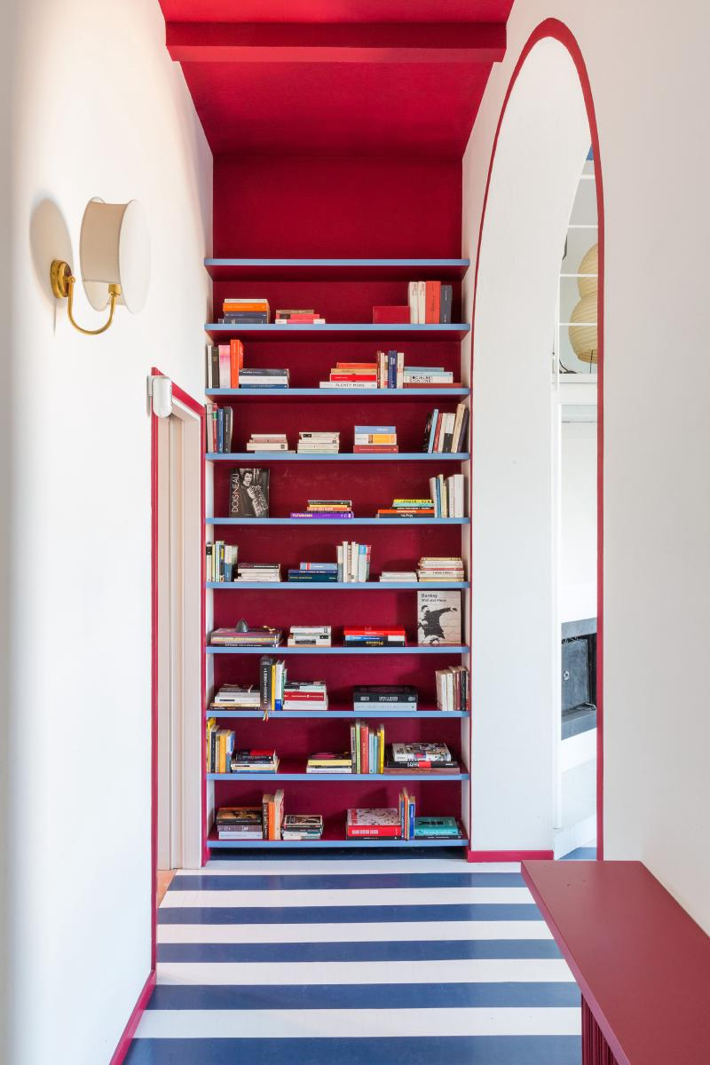 Plafond peint en rouge pour cette entrée, en continuité avec le mur bibliothèque du fond Plafond peint en rouge pour cette entrée, en continuité avec le mur bibliothèque du fond