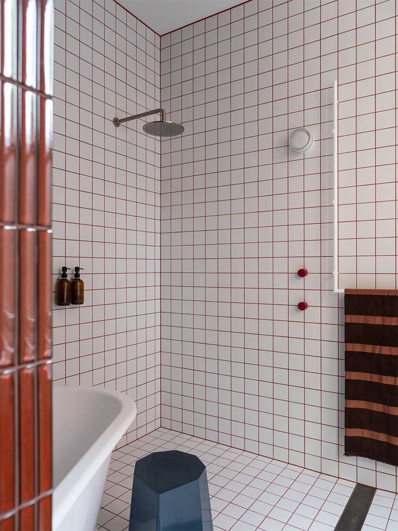 Douche à l'italienne avec des carreaux de faïence blancs et joints rouges