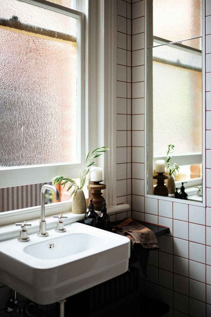 Une salle de bains avec un lavabo au look rétro pour cette salle de bains aux carreaux de faïence blancs