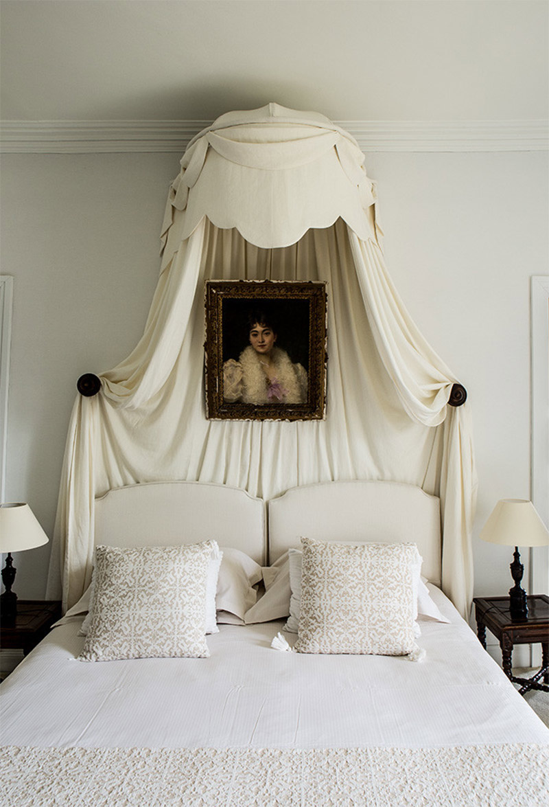 Un lit avec une tête de lit drapé pour une chambre classique historique, modernisée par le choix du blanc Un lit avec une tête de lit drapé pour une chambre classique historique, modernisée par le choix du blanc