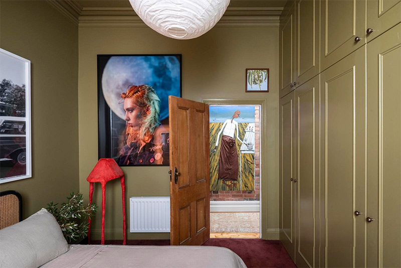 Une chambre traitée en "color drenching" vert olive avec une lampe rouge qui attire le regard Une chambre traitée en "color drenching" vert olive avec une lampe rouge qui attire le regard