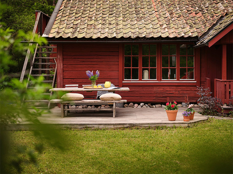 Vue extérieure de la maison peinte en rouge avec sa terrasse aménagée Vue extérieure de la maison peinte en rouge avec sa terrasse aménagée
