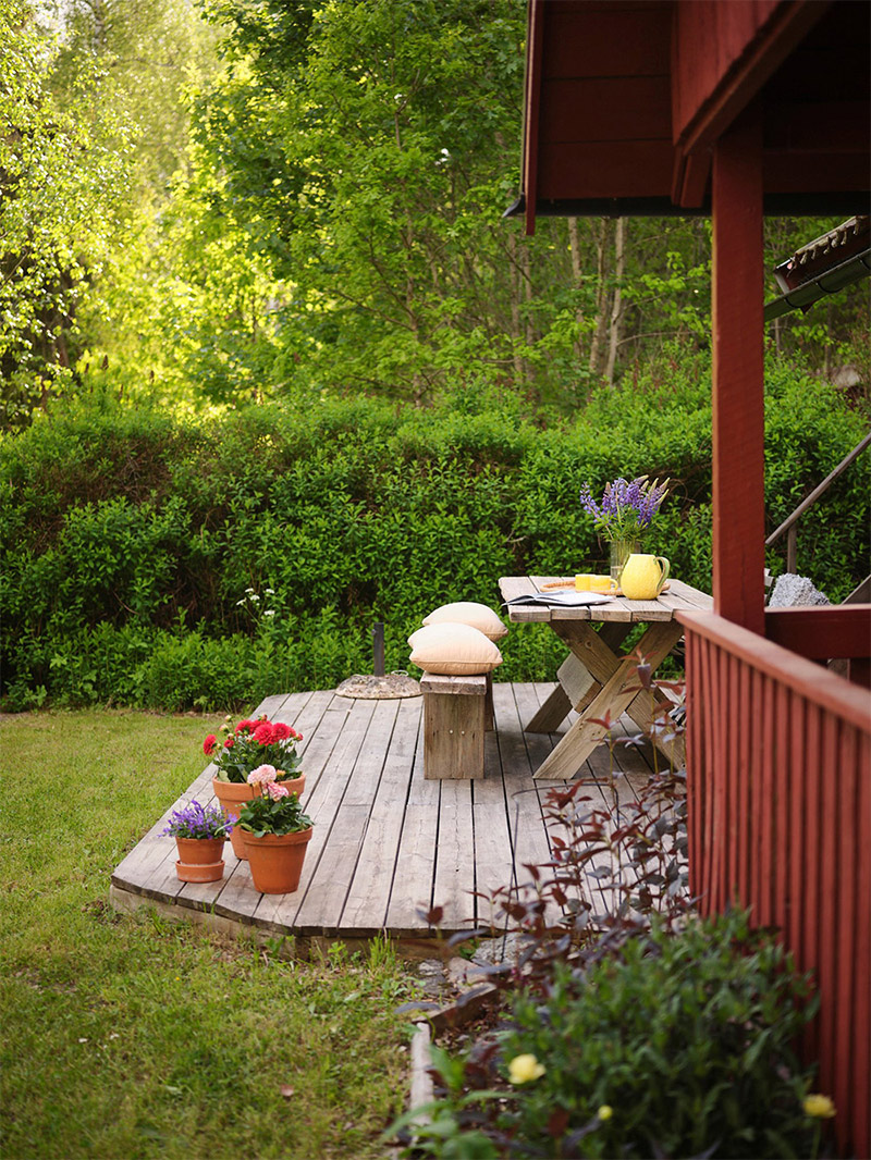 Vue extérieure de la maison peinte en rouge avec sa terrasse aménagée Vue extérieure de la maison peinte en rouge avec sa terrasse aménagée