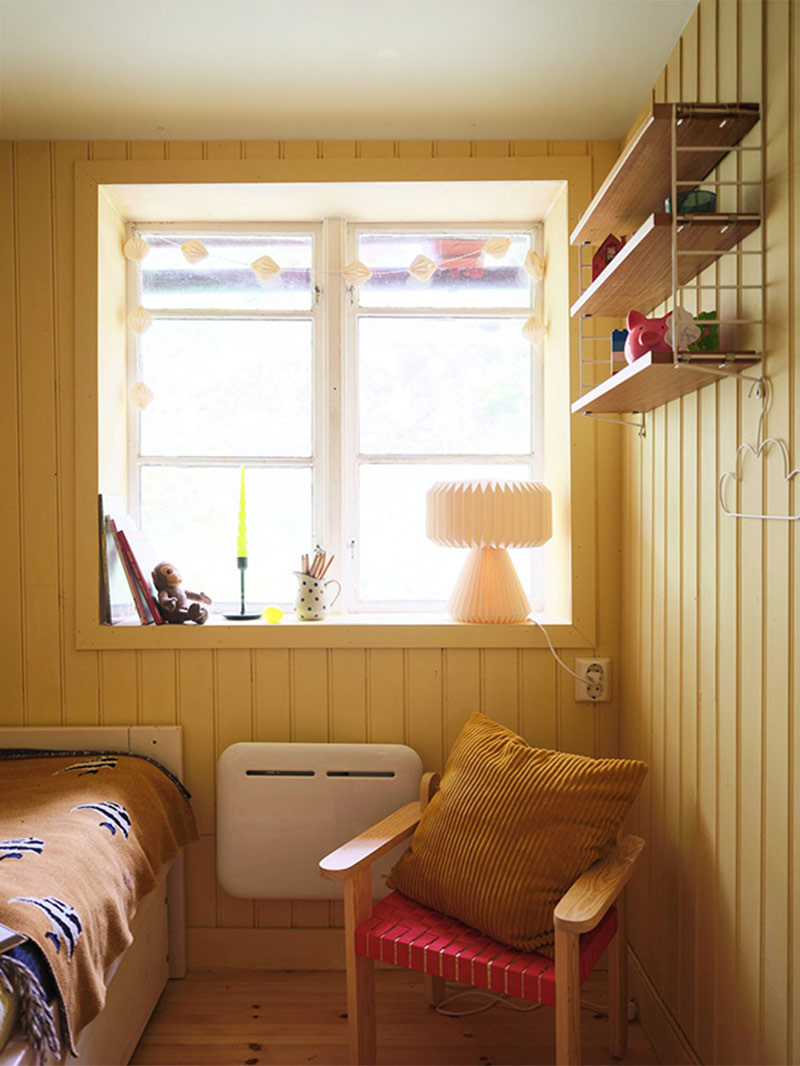 Petite chambre sous les combles avec des lambris peints en jaune Petite chambre sous les combles avec des lambris peints en jaune